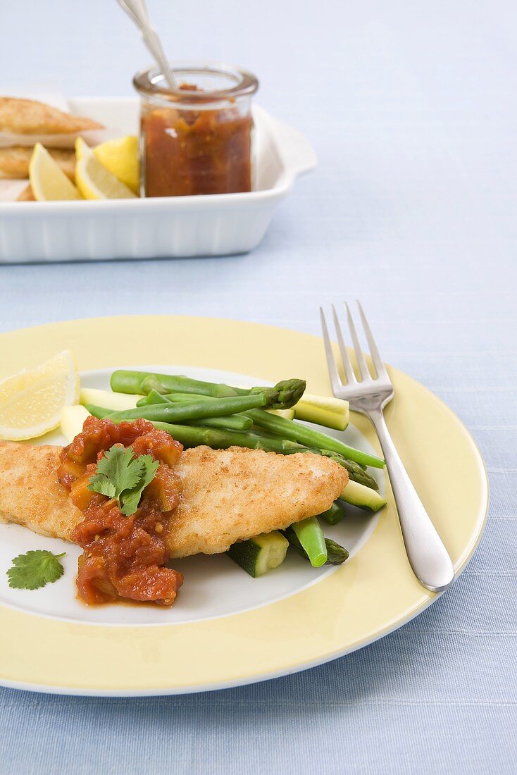 Panierte Fischfilets auf grünem Gemüse