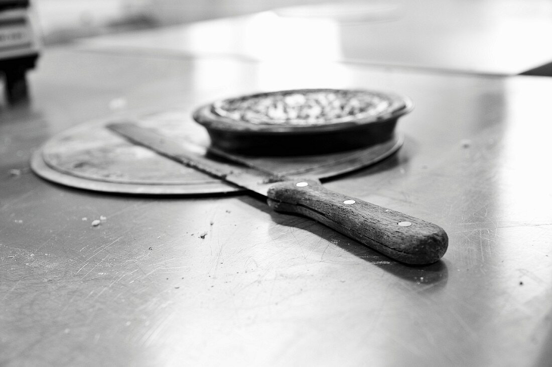 Messer und Backutensilien auf Edelstahlplatte in der Küche