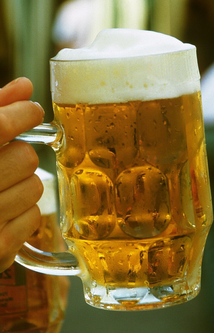 Hand hält Halbliterglas mit frischem Bier