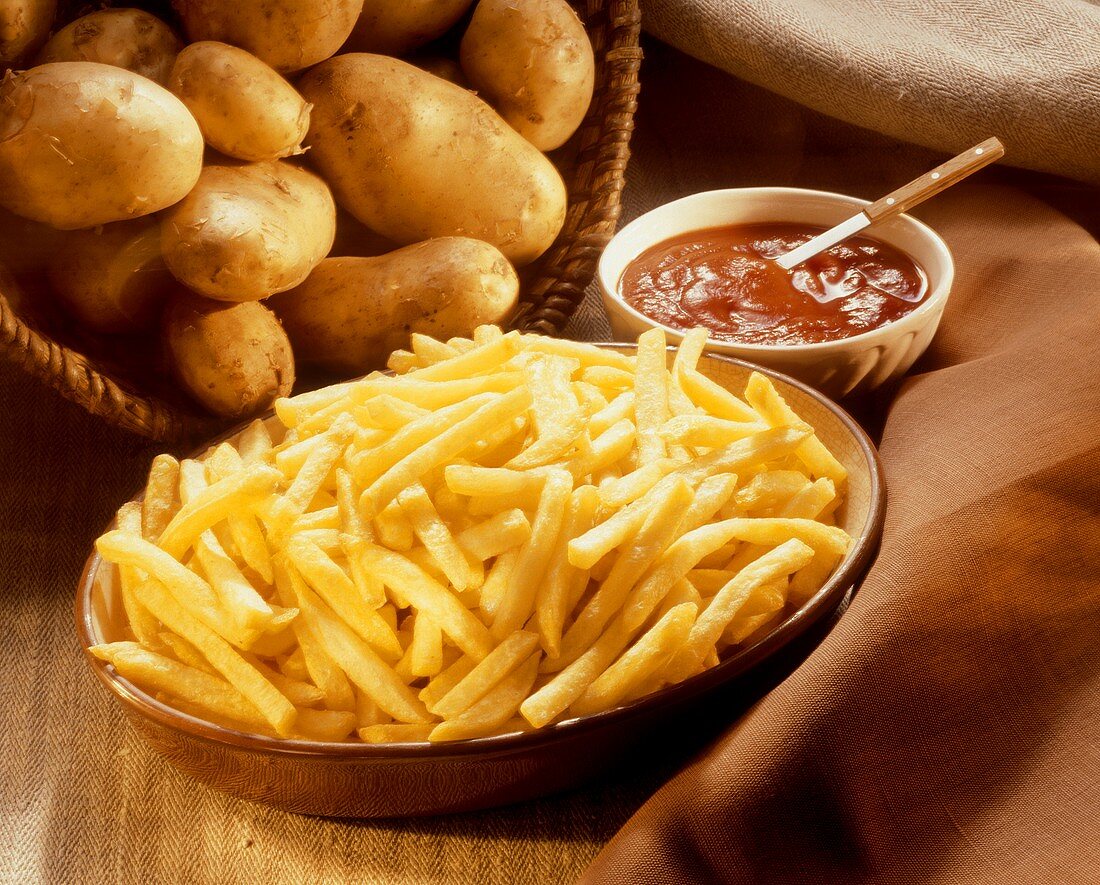 French Fries in a Bowl shown with Uncooked Whole Potatoes
