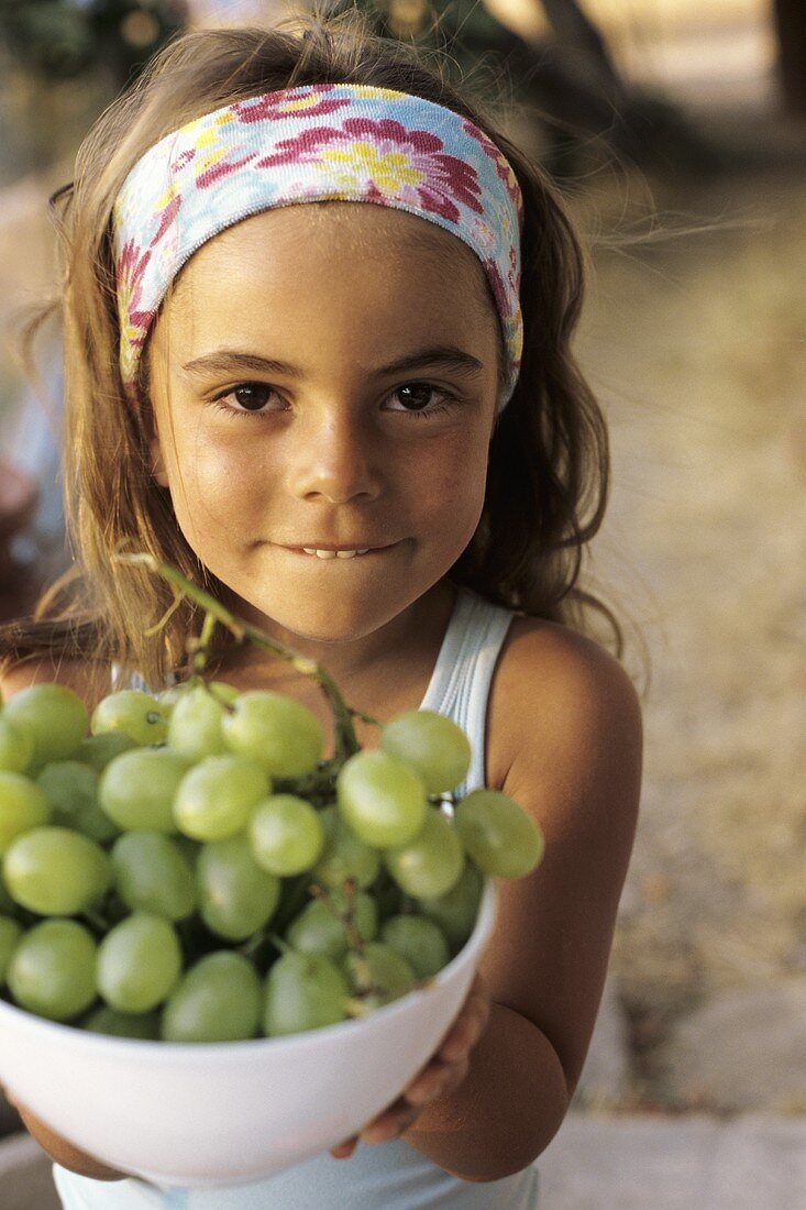 Young girl holding bowl of grapes
