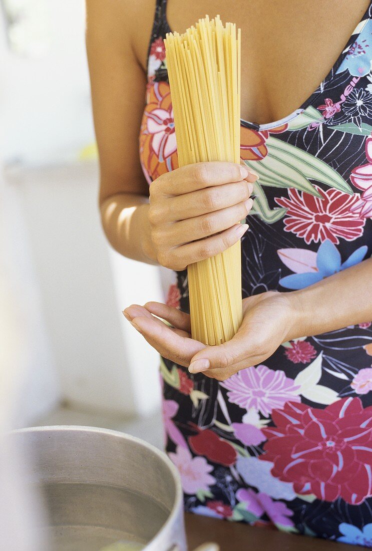 Junge Frau hält ungekochte Spaghetti in der Hand
