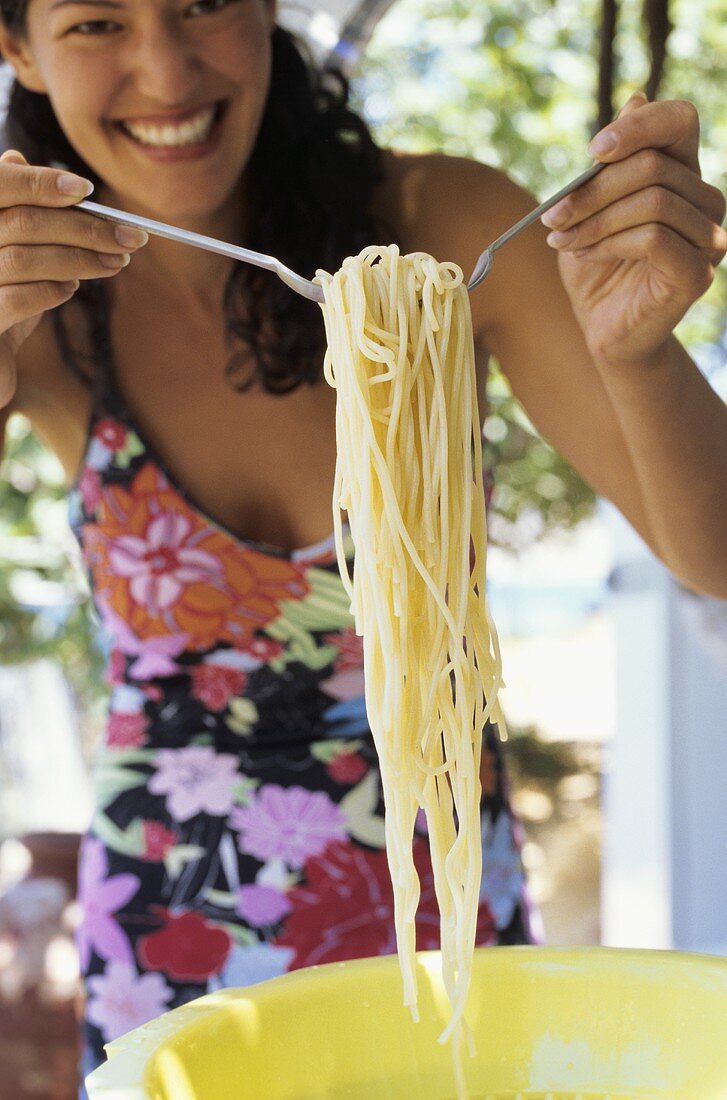 Junge Frau nimmt sich Spaghetti aus einem Plastikseiher