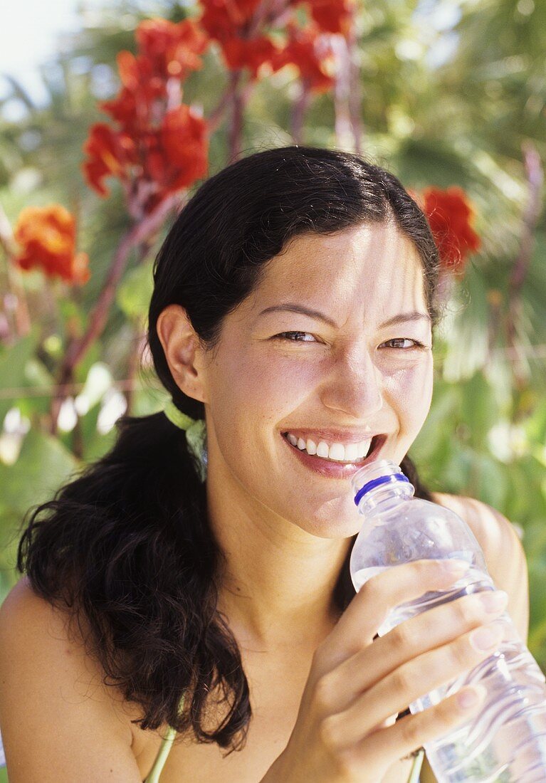 Young woman drinking mineral water in the shade