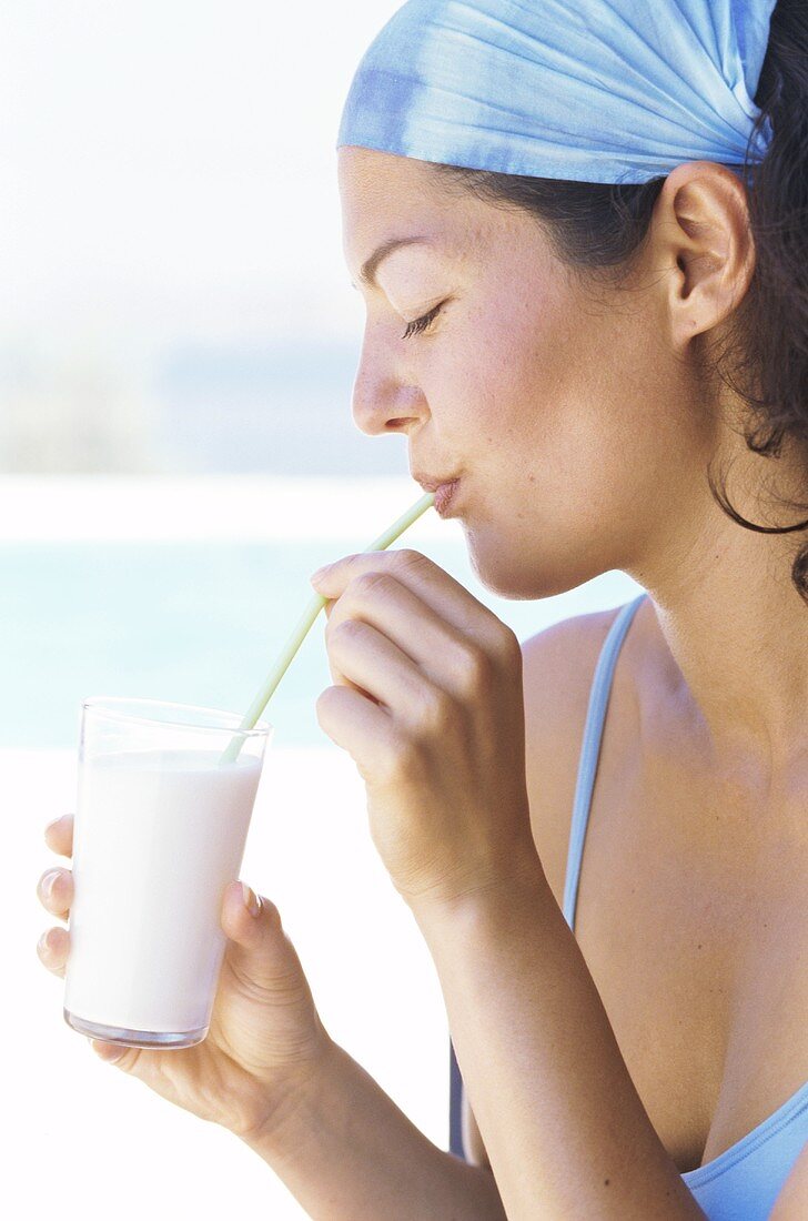 Young woman drinking milkshake on beach
