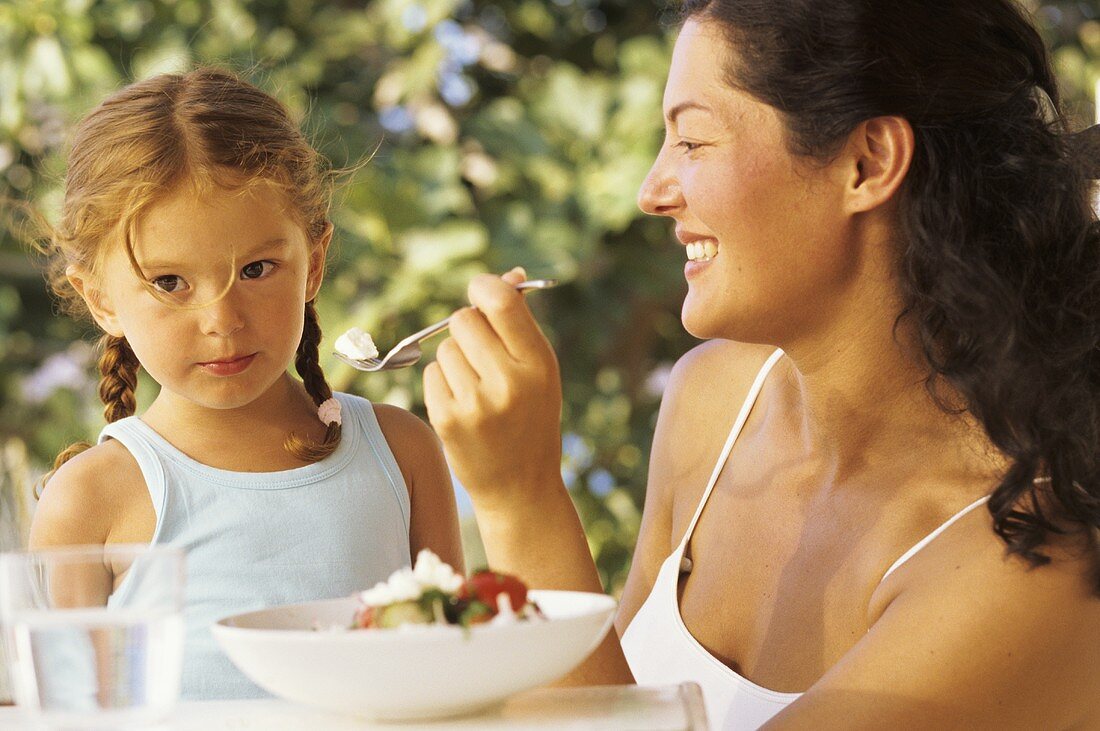 Mother and daughter eating salad in open air