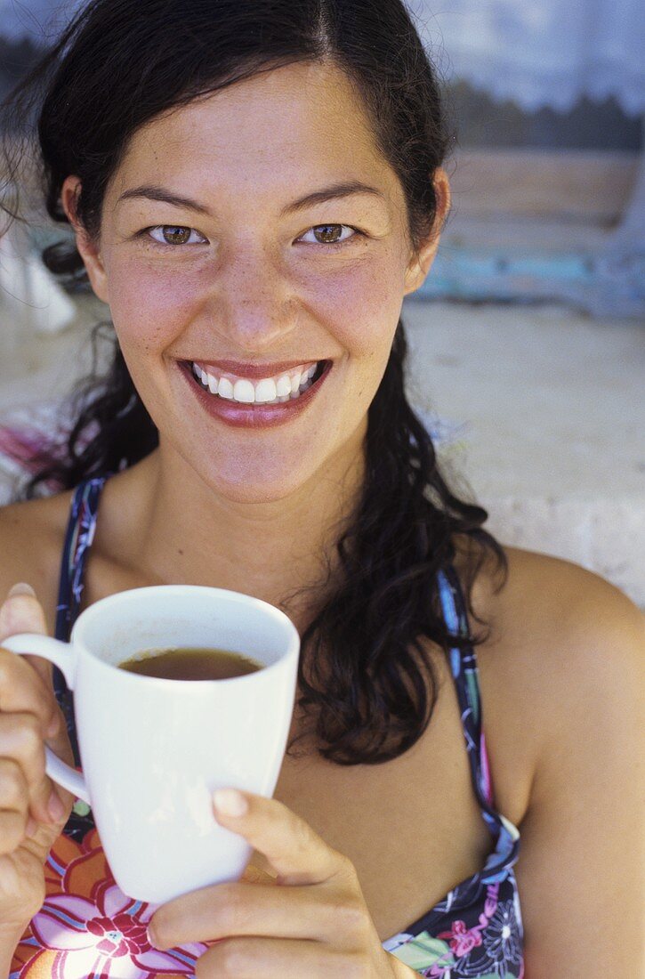 Junge Frau trinkt Kaffee am Strand