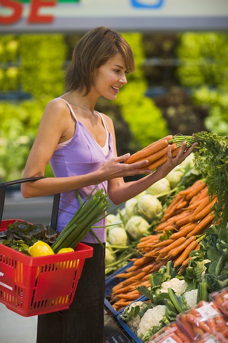 Junge Frau vor Gemüsetheke im Supermarkt
