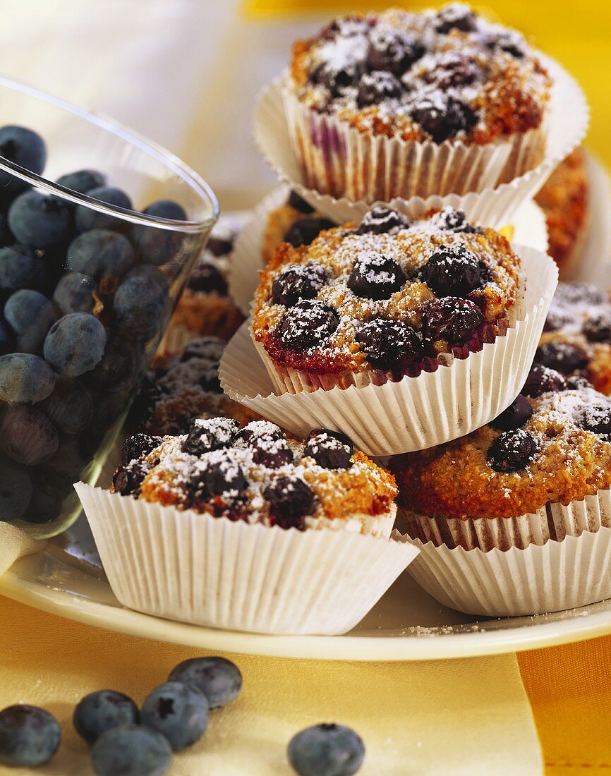 Blueberry muffins with icing sugar; blueberries in glass