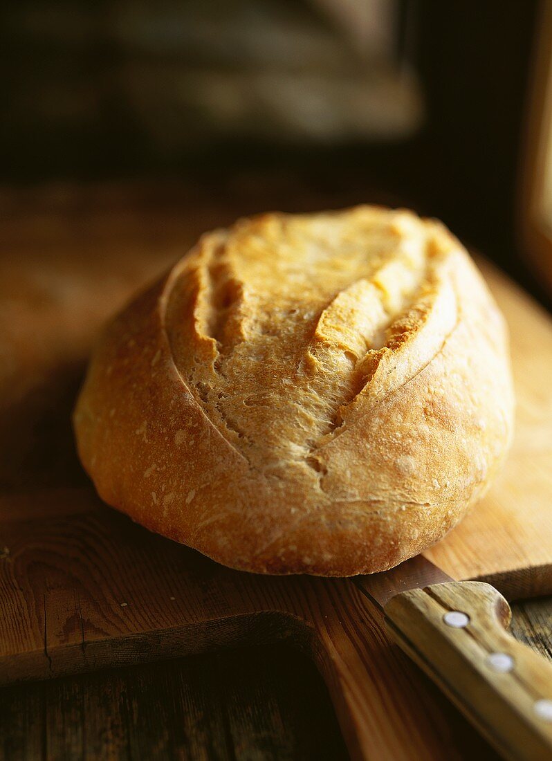 Crusty loaf of bread on chopping board