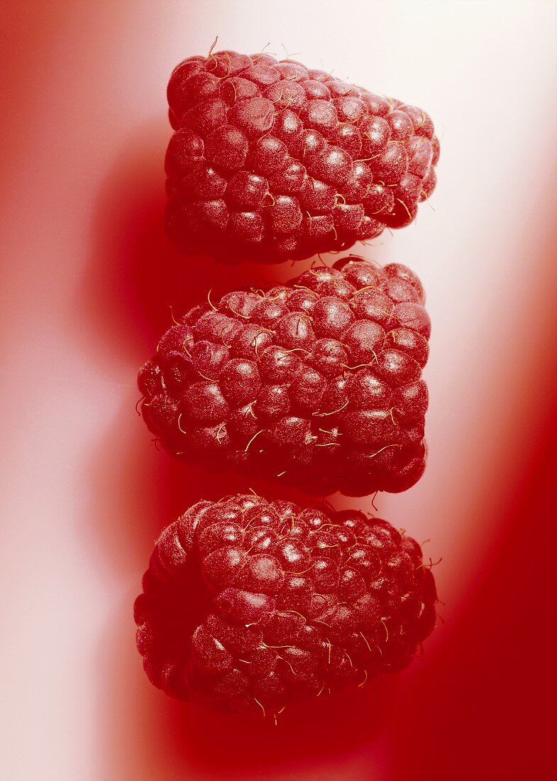 Three raspberries on red background