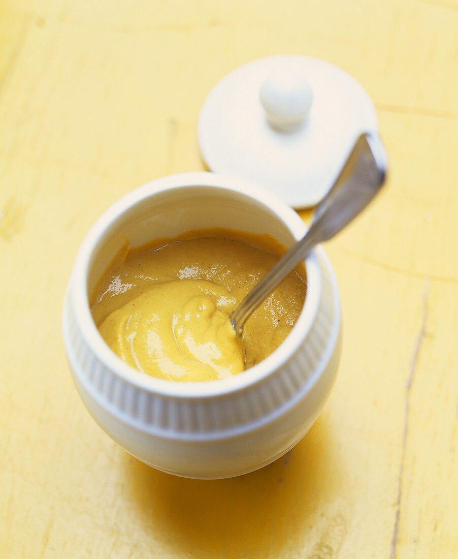 Mustard in white bowl with spoon