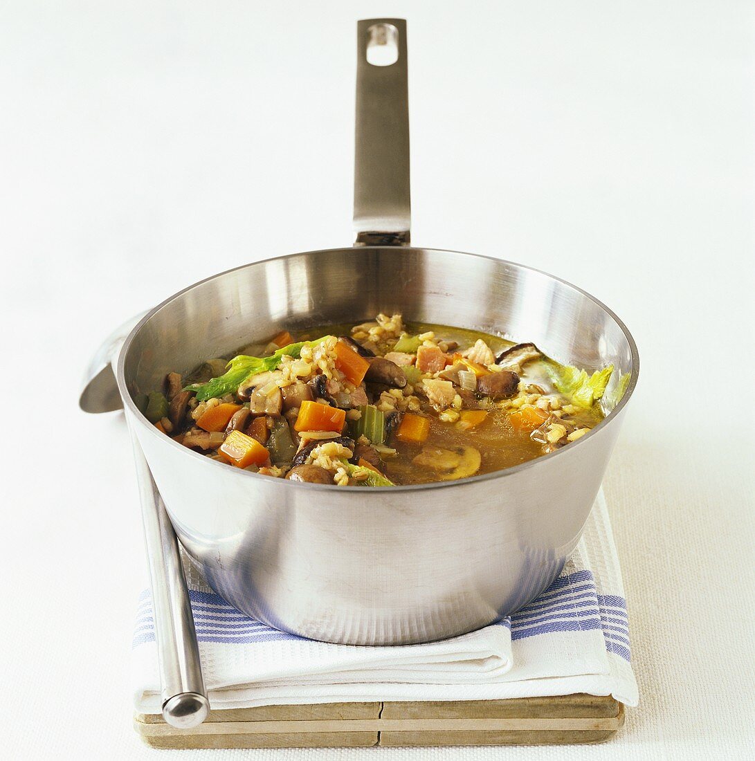 Gemüsesuppe mit Pilzen, Graupen und Speck im Kochtopf