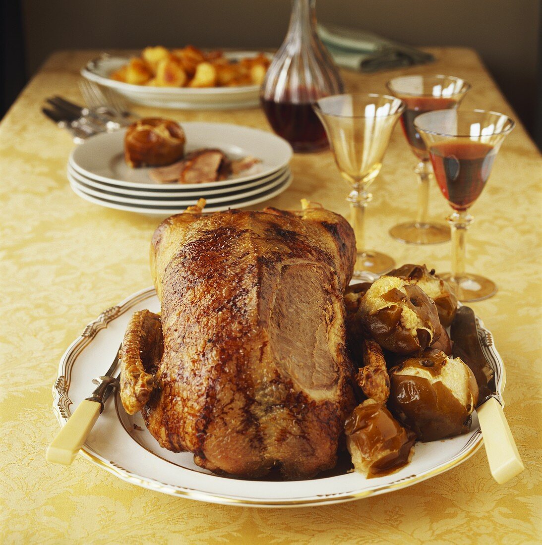 Roast goose with potatoes and red wine on laid table