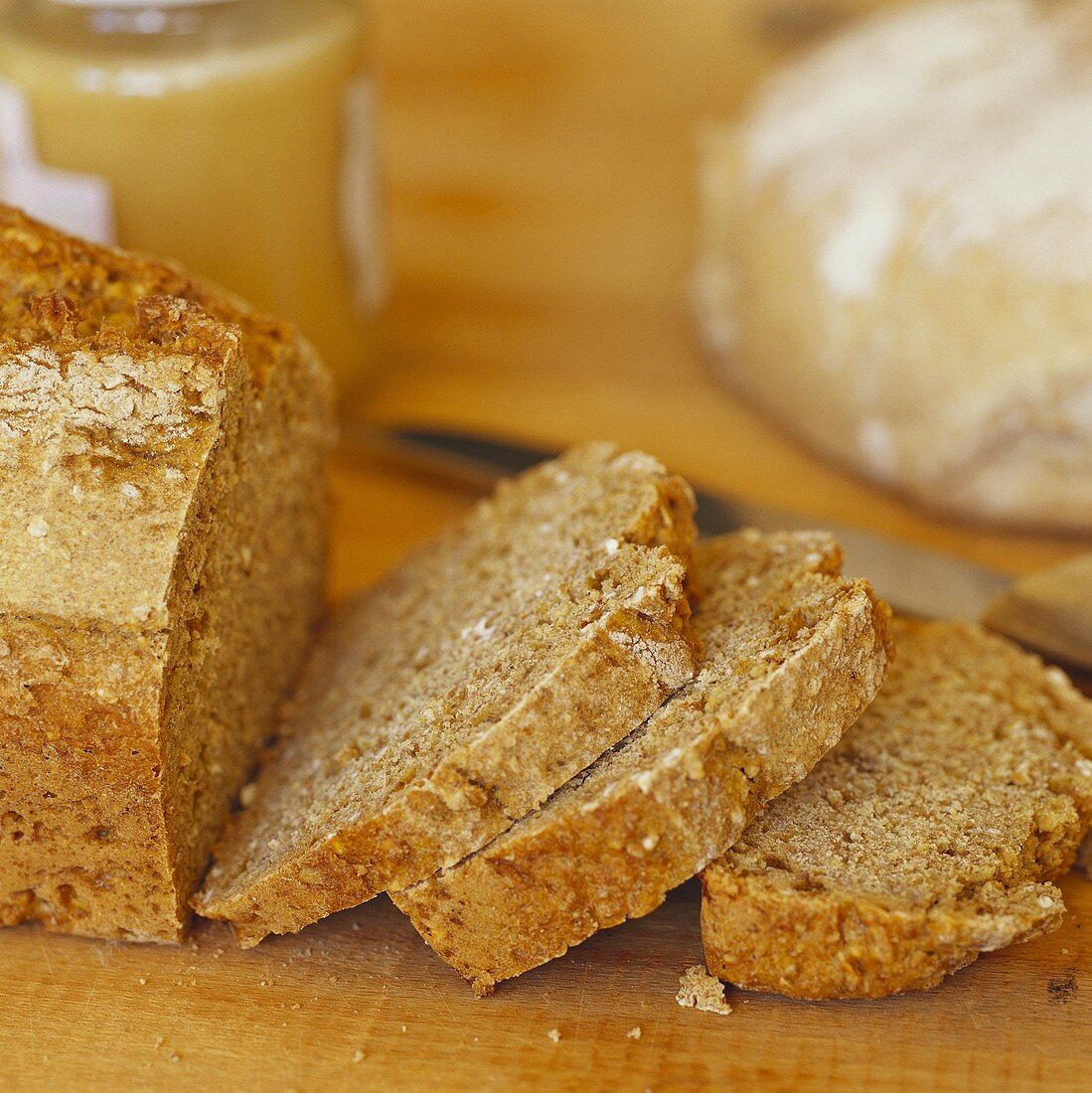 Wholemeal bread, slices cut, jar of honey behind