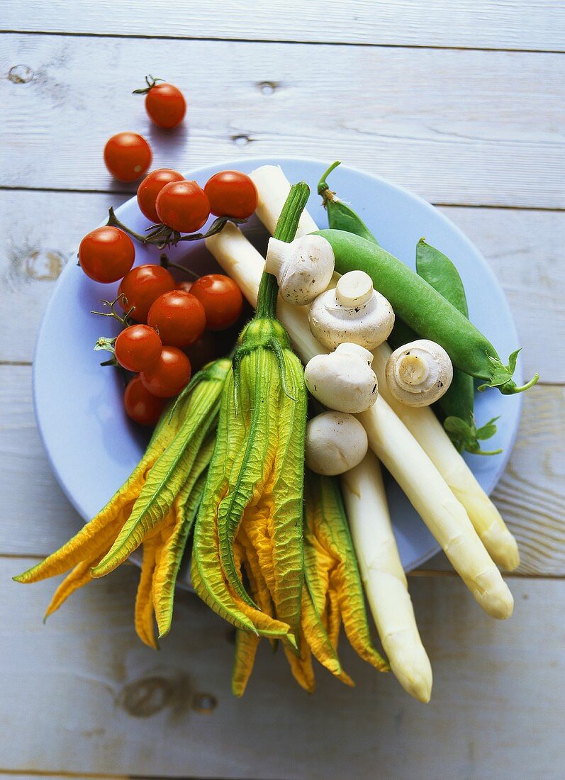 Gemüse, Zucchiniblüten und Champignons auf blauem Teller