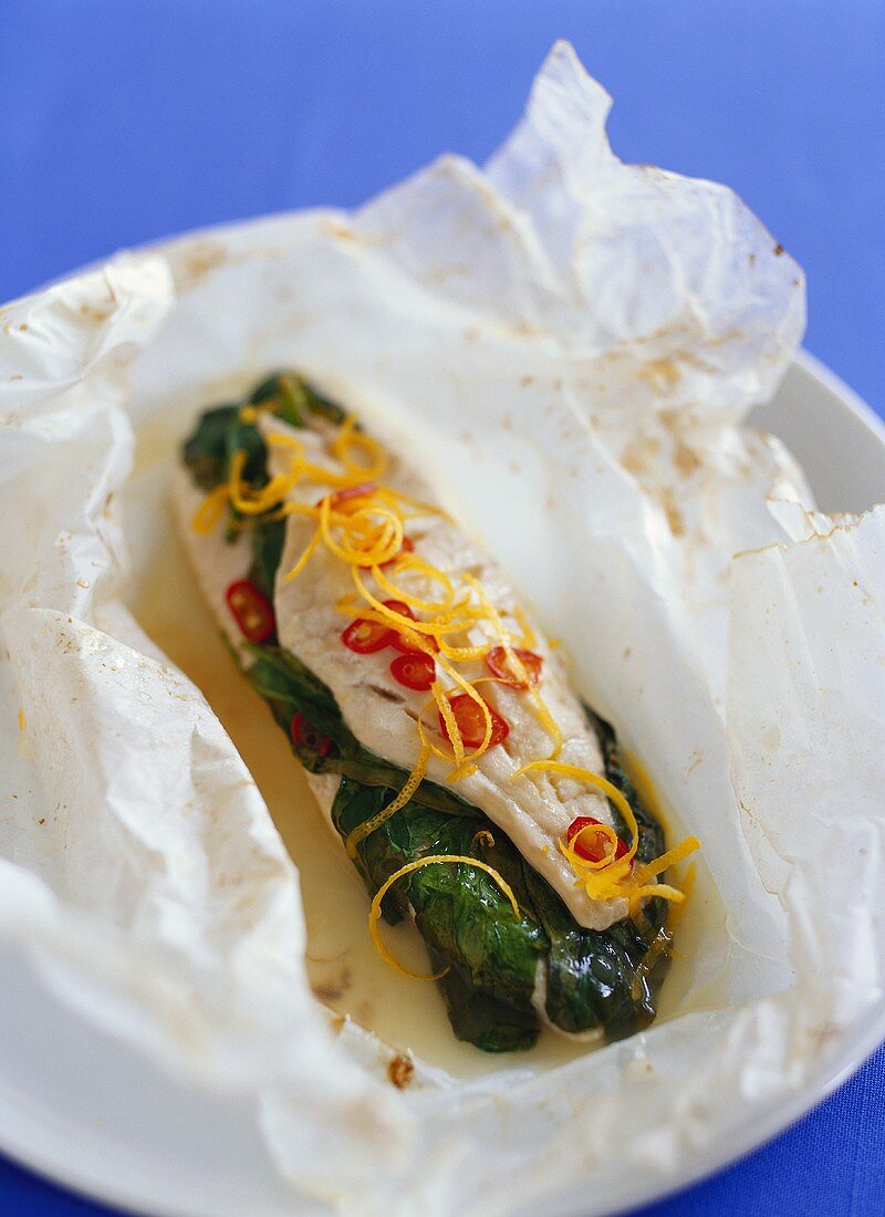 Fish fillets with spinach, chili and lemon zest in paper