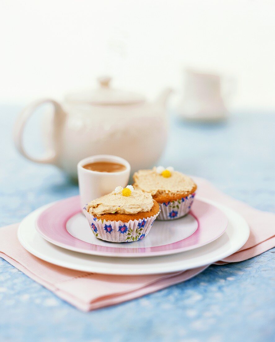 Muffins with cream in paper cases; coffee