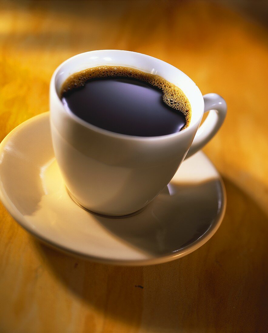 Schwarzer Kaffee in weisser Tasse auf Holzuntergrund