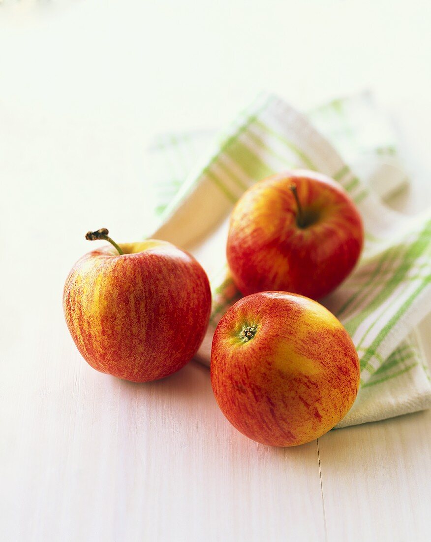 Three red apples on green and white cloth