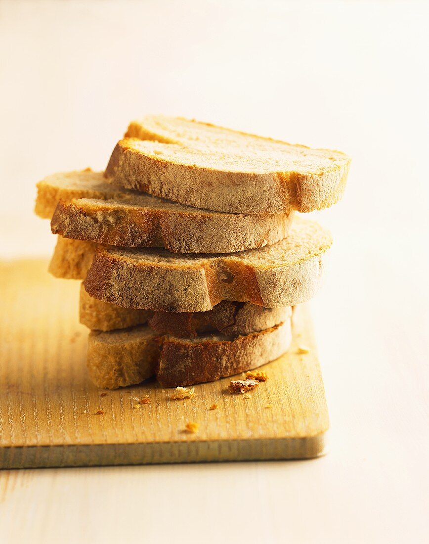 Slices of bread, in a pile on wooden board