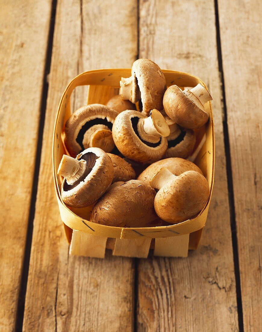 Brown mushrooms in chip basket on wooden background
