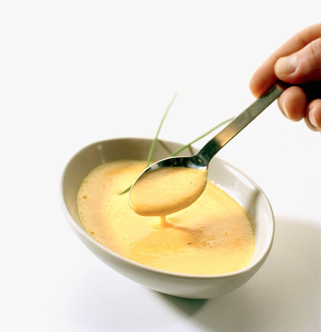 Hand holding spoonful of white sauce