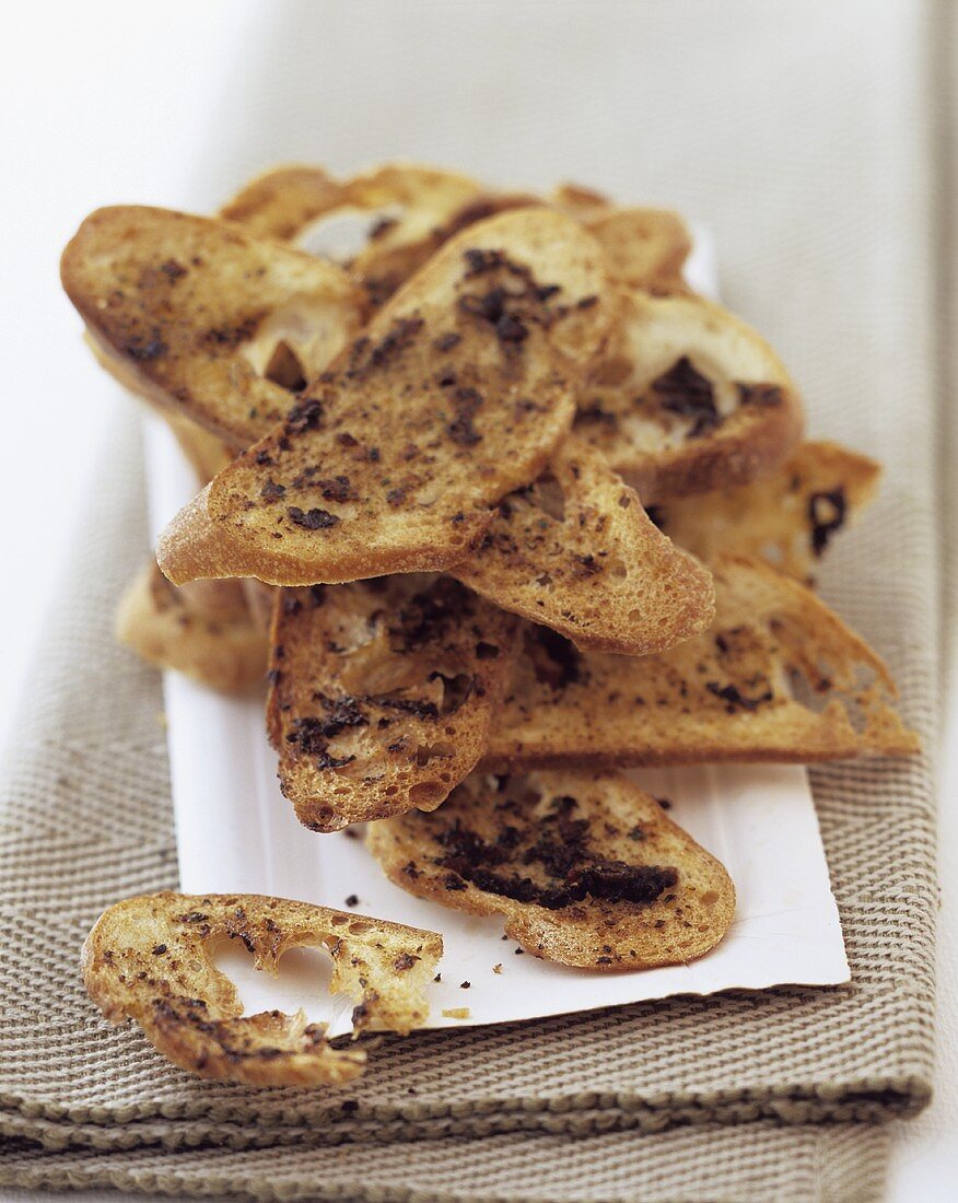 Crisp olive bread in slices on napkin