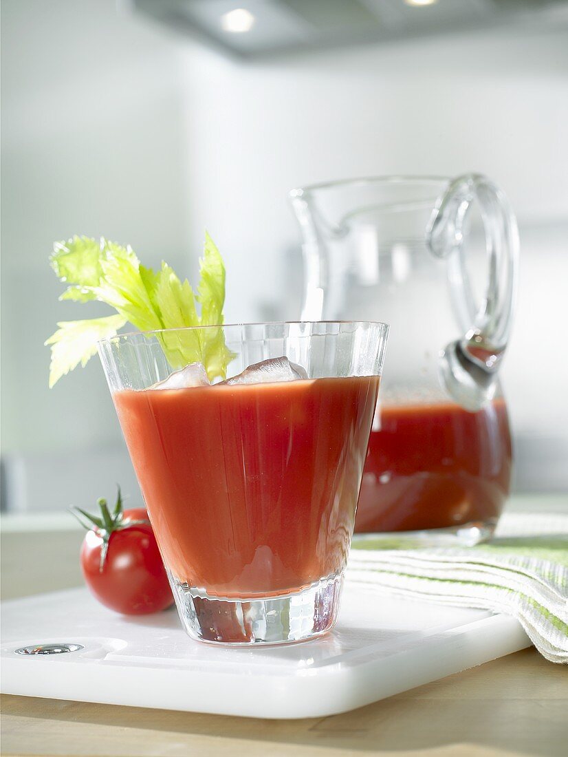 Tomato juice in glass with ice cubes and celery