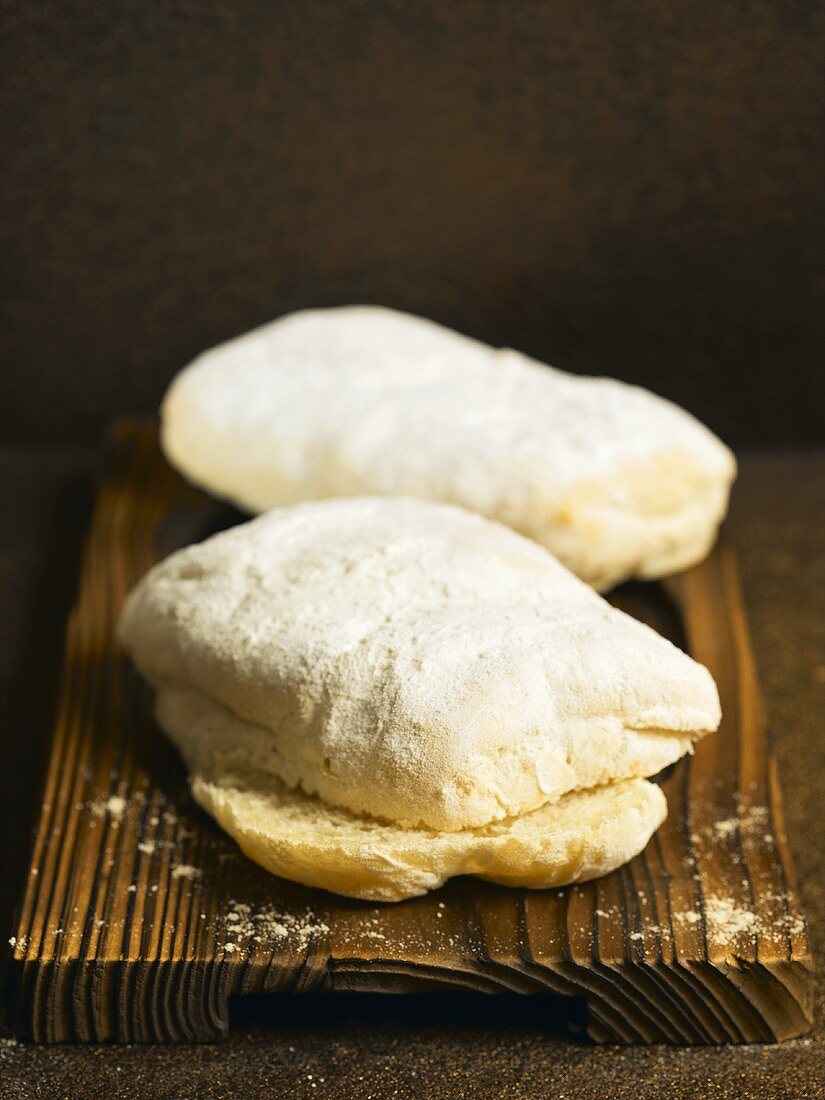 Two ciabattas on wooden chopping board