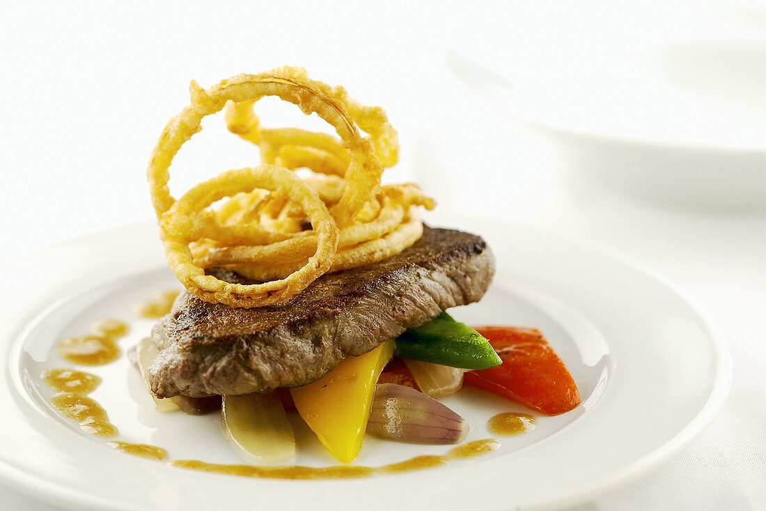 Steak with deep-fried onion rings on vegetables