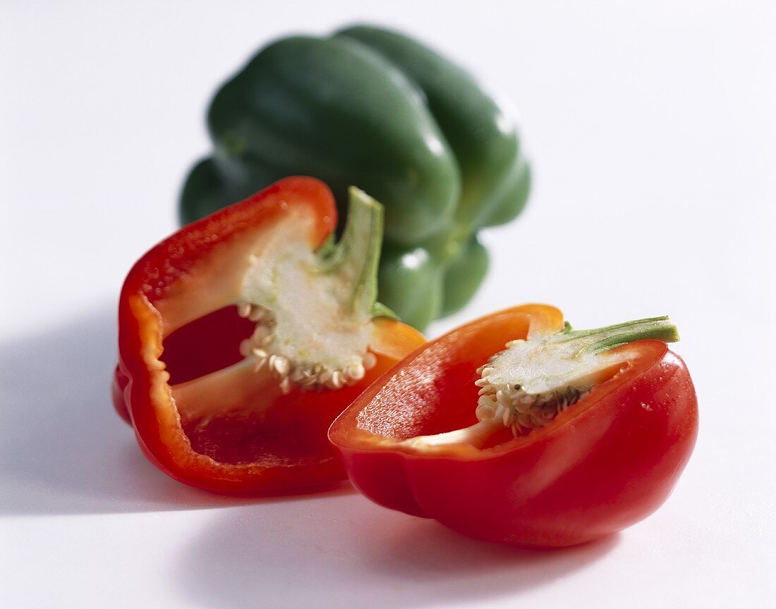 Halved red pepper in front of green pepper