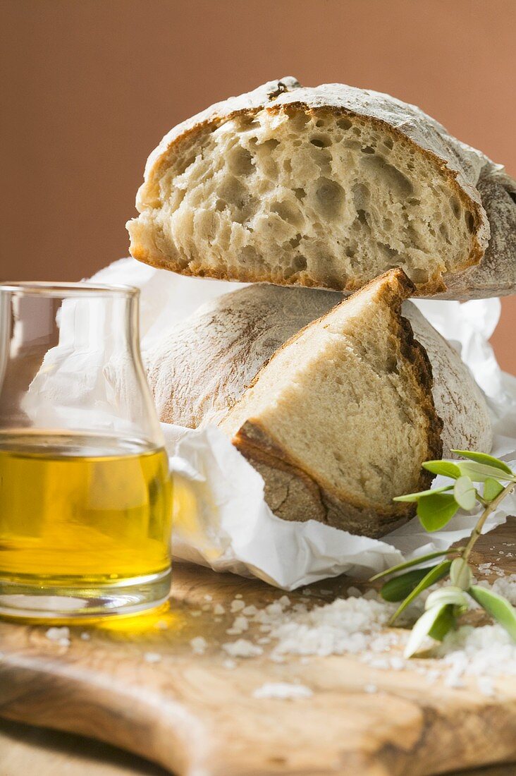 Rustic bread on paper, salt and olive oil beside it