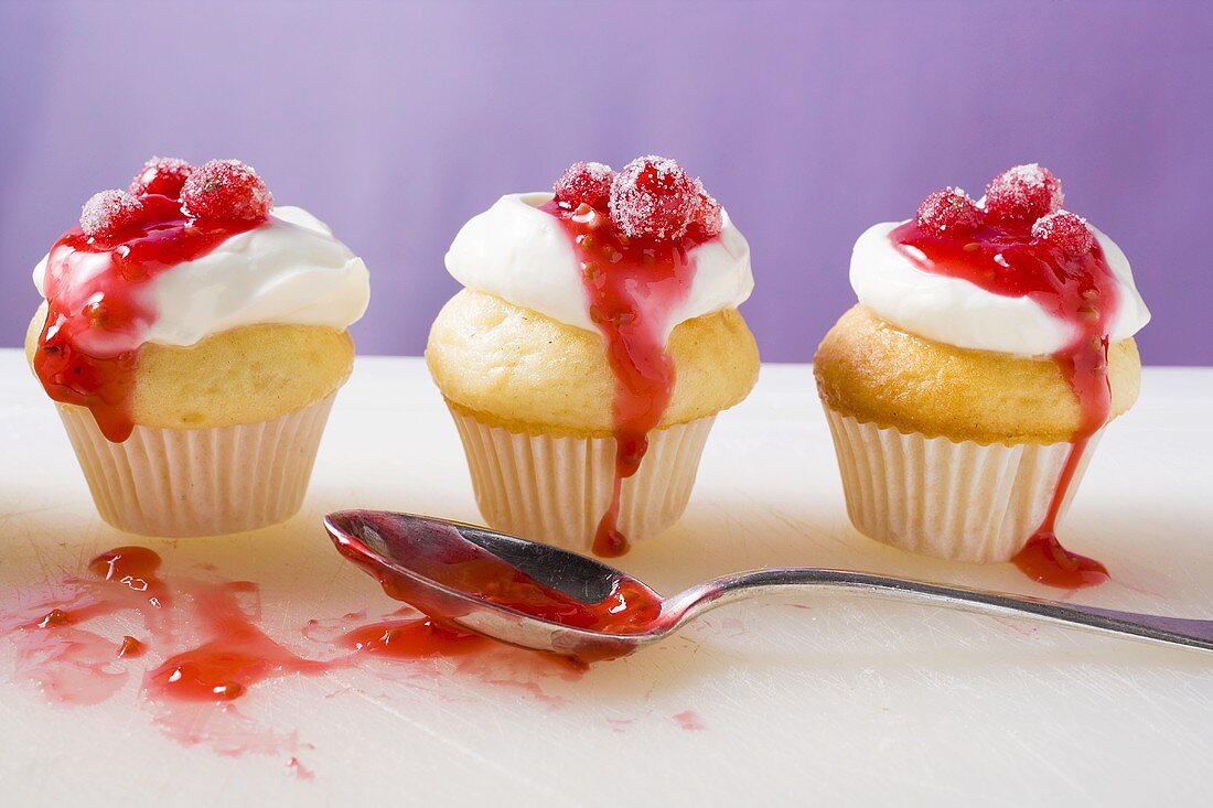 Drei Muffins mit Sahne und roten Johannisbeeren