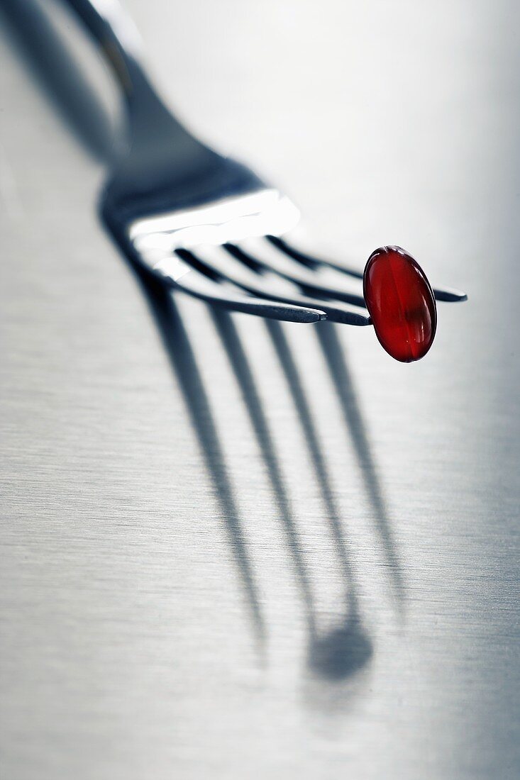 Red vitamin capsule on fork