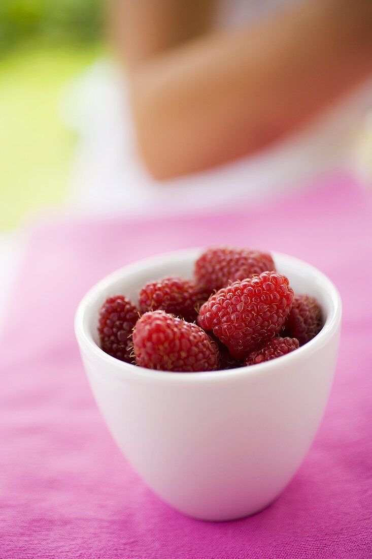 Ein Schälchen Himbeeren auf Tisch im Freien