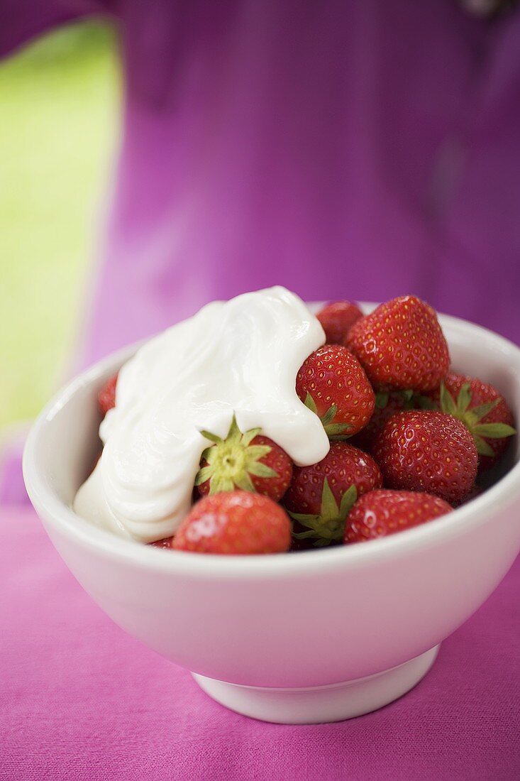 Frische Erdbeeren mit Sahne auf Tisch im Freien