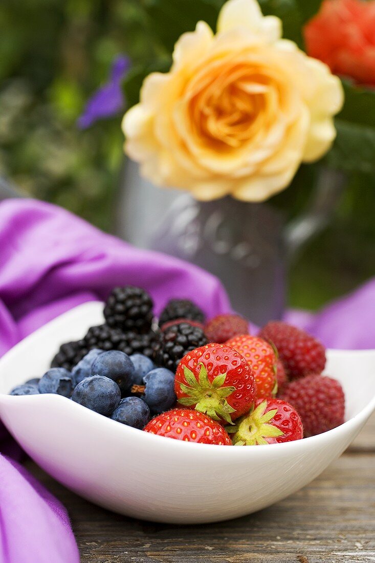 Fresh berries in white bowl on table in the open air