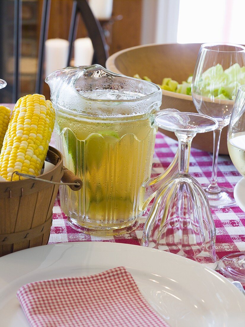 Laid table with corn cobs, drink and salad (USA)