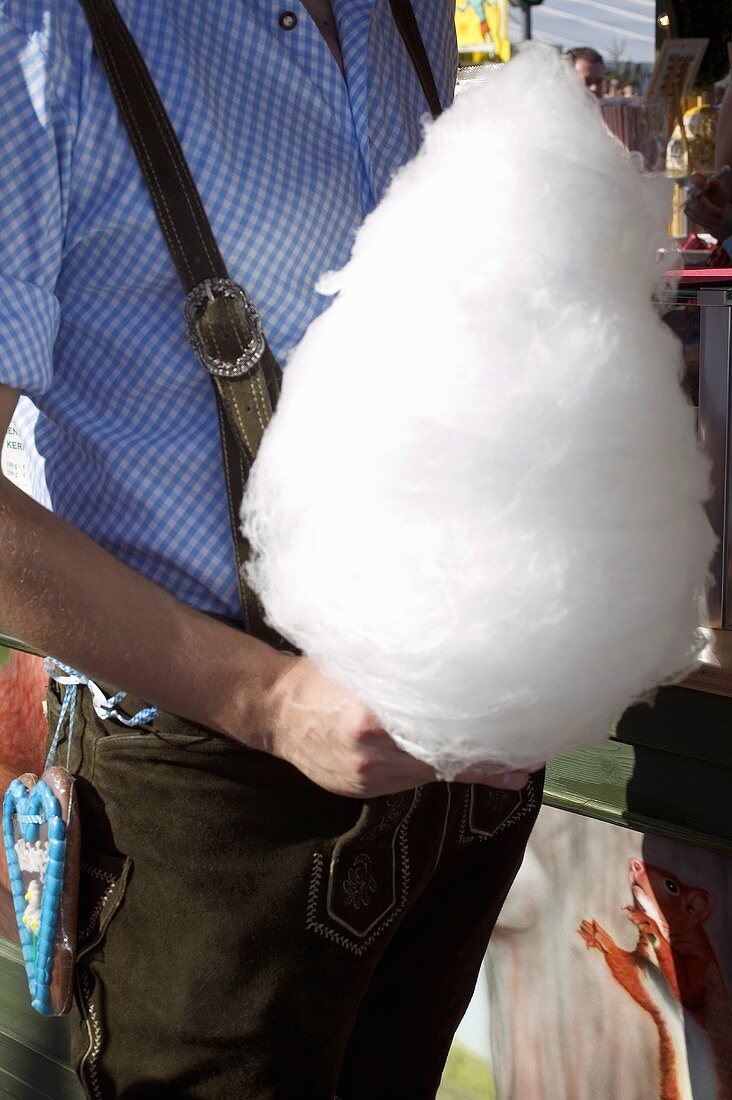 Man in national dress holding candyfloss (Oktoberfest, Munich)