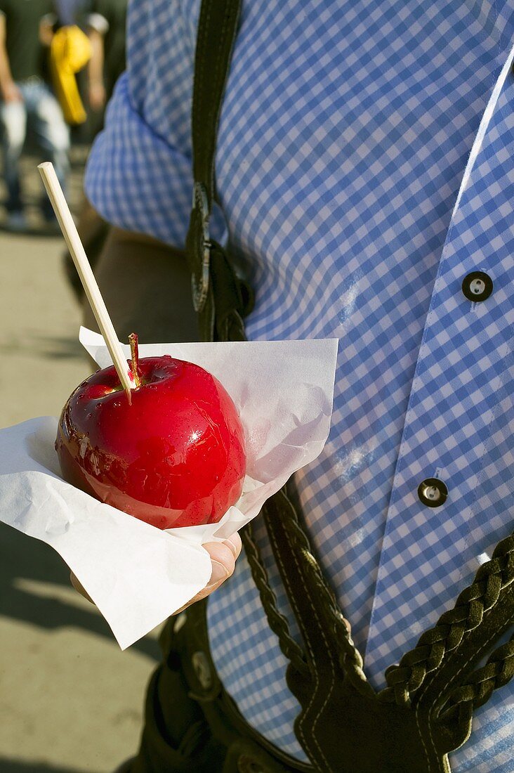 Man in national dress holding toffee apple (Oktoberfest, Munich)