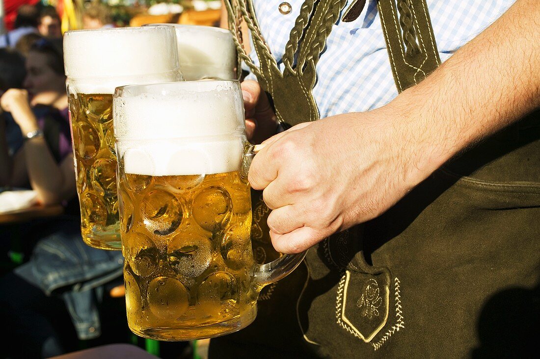Mann in Tracht hält drei Mass Bier (München, Oktoberfest)