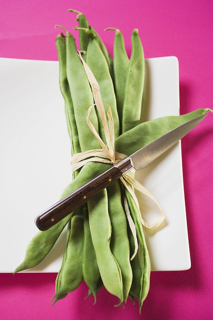 A bundle of green beans with knife