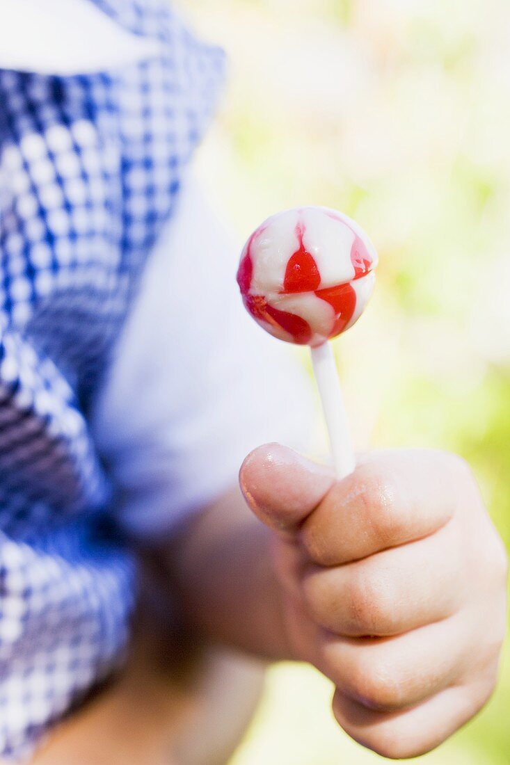 Child's hand holding a lollipop