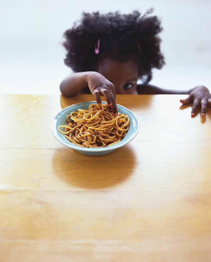 Kleines Mädchen greift nach Spaghetti Bolognese