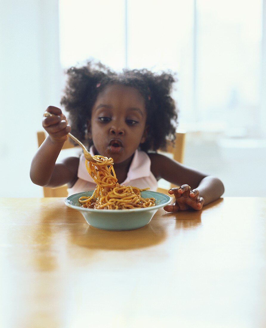 Small girl eating spaghetti bolognese