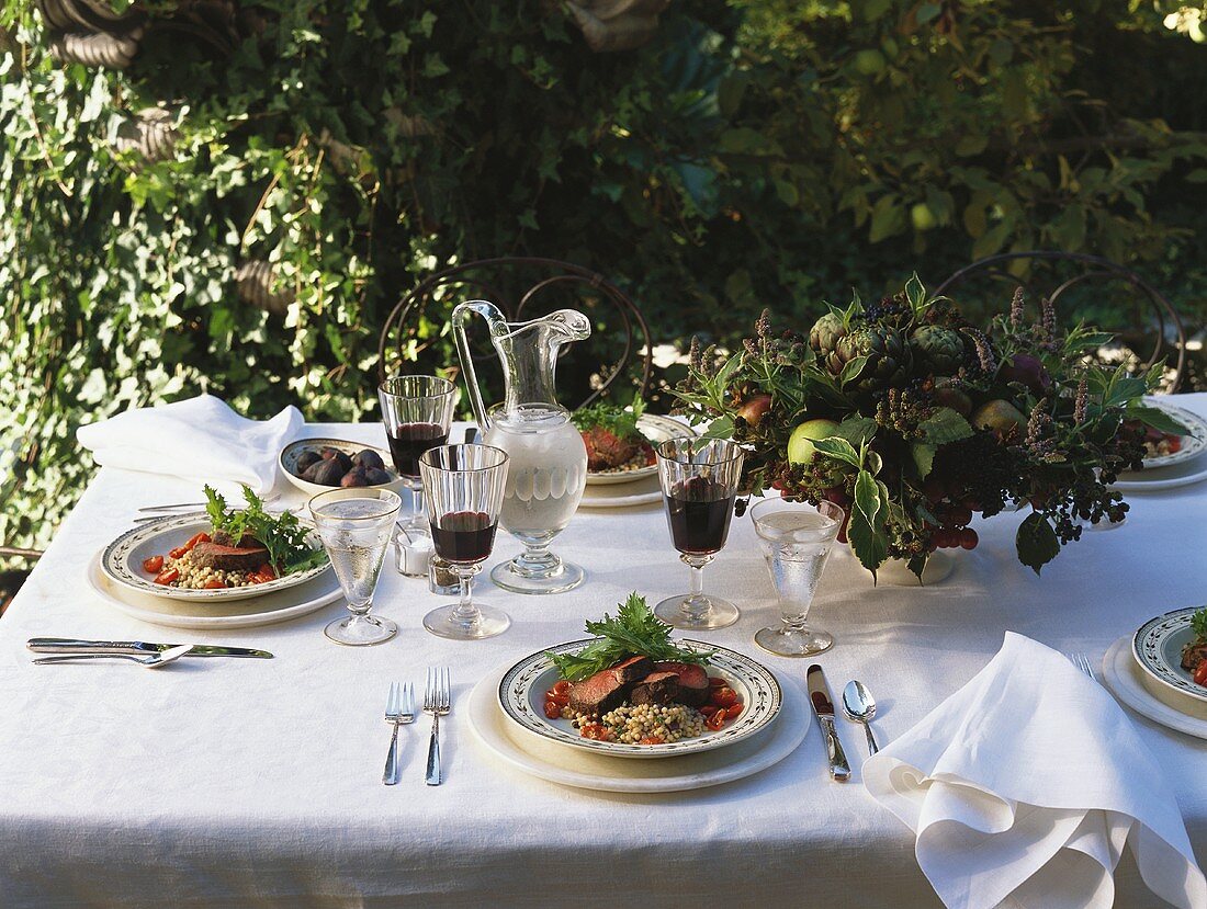 Gedeckter Tisch im Freien mit Steak und Rotwein