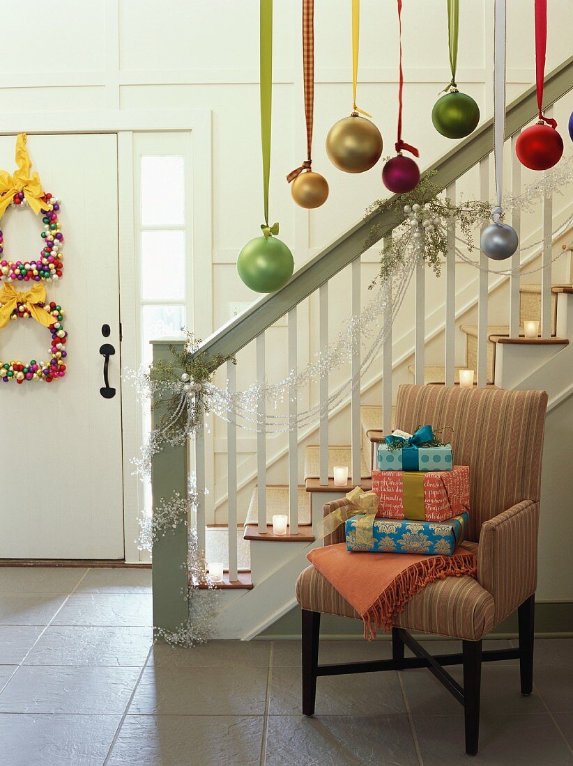 Christmas gifts on chair beside decorated staircase