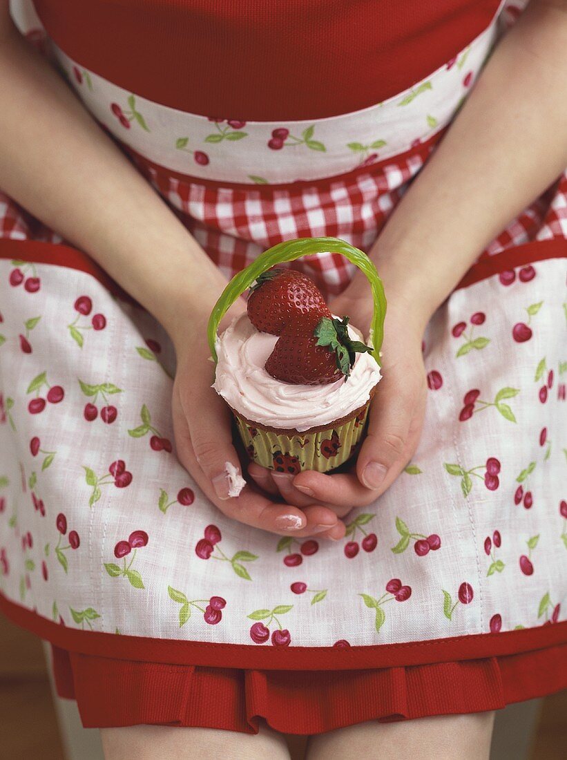 Mädchen hält Cupcake mit Erdbeeren