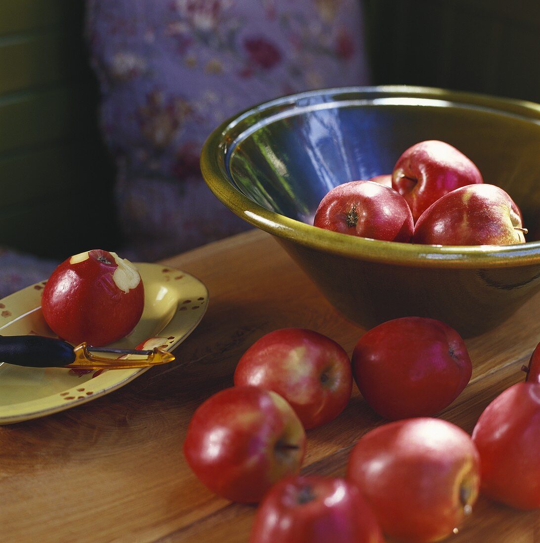 Red apples in bowl, on wooden table and on plate